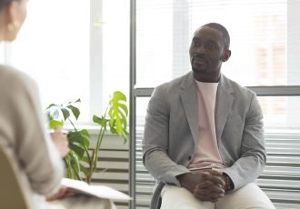 man-being-interviewed-indoors-by-journalist-min